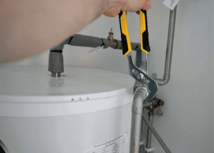 wrench being used to tighten a pipe on a hot water cylinder